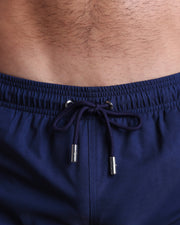 Close-up view of the IMPERIAL BLUE men’s summer shorts, showing light blue cord with custom branded silver cord ends, and matching custom eyelet trims in black.