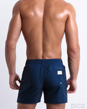 Back view of the IMPERIAL BLUE beach Resort Shorts in a solid navy blue color with white and red side stripes, complete the back pockets, made by DC2 a capsule brand by BANG! Clothes in Miami.