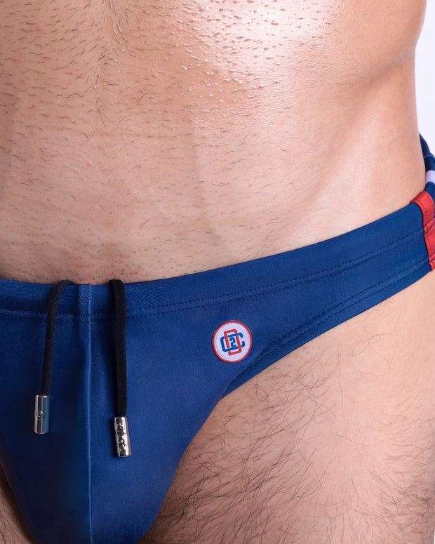 Close-up view of the IMPERIAL BLUE men’s drawstring briefs showing black cord with custom branded metallic silver cord ends, and matching custom eyelet trims in silver.