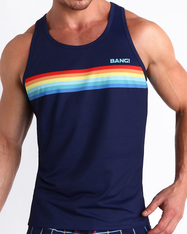 Front view of model wearing the INFINITY STRIPES men’s beach tank top in a navy dark blue color with rainbow stripes by the Bang! Clothes brand of men&