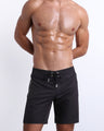 Model wearing the Jet Black Flex Boardshorts with a lace-up front, longer leg cut, and zippered side pockets.