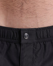 Close-up view of the men’s summer mini shorts, showing custom branded metal button in metallic silver.