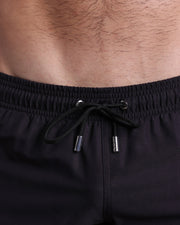 Close-up view of the JET BLACK men’s summer shorts, showing black cord with custom branded silver cord ends, and matching custom eyelet trims in silver.