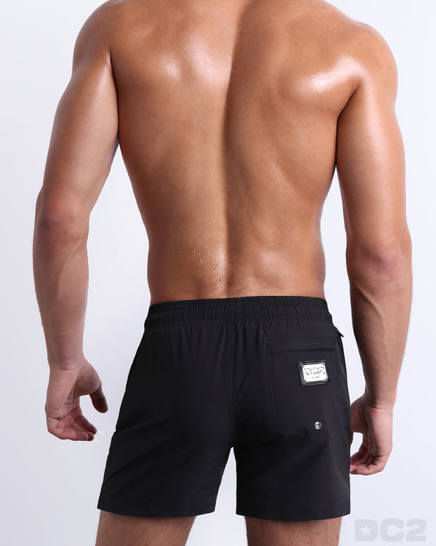 Back view of the JET BLACK beach Resort Shorts in a solid black color, complete with a back pocket, designed by DC2 a capsule brand by BANG! Clothes based in Miami.