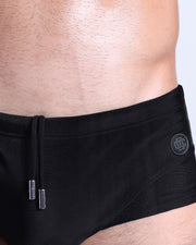 Close-up view of the JET BLACK men’s drawstring briefs showing black cord with custom branded metallic silver cord ends, and matching custom eyelet trims in silver.