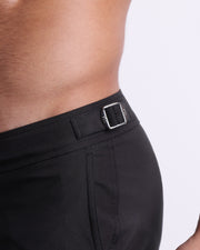Close-up view of the JET BLACK men’s swimwear, showing custom branded silver metal adjustable side buckles.