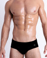 DC2 Spring/Summer 2025 collection — model wearing JET BLACK swim briefs, featuring a sleek low-rise silhouette in deep black.