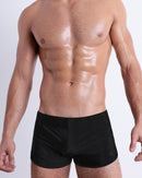 Front view of model wearing the JET BLACK men’s swimming bottoms in a solid black color by DC2, a men's beachwear brand from Miami.