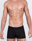 DC2 JET BLACK Swim Trunks — model wearing square-cut swim trunks, featuring sleek skin-hugging fit and matte black finish.