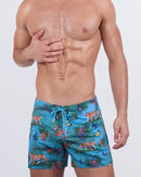  A male model wearing the JUNGLE BOOGIE - Flex Shorts by DC2 Miami. These vibrant shorts feature a striking jungle-inspired print with tigers, butterflies, and tropical foliage on a blue-green leopard print background.