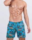 Frontal view of a male model wearing the JUNGLE BOOGIE Resort Shorts for men by DC2 Miami. These above-the-knee swim shorts feature a vibrant jungle-inspired print with tigers, tropical flora, and a blue leopard pattern. Designed with an elastic waistband, adjustable drawstring, and a relaxed fit, these shorts are ideal for summer getaways, beach parties, and poolside lounging.
