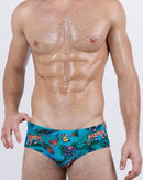 Model wearing Jungle Boogie men's swim briefs by DC2 BANG – designer swimwear with tropical jungle print, tigers, and butterflies – sexy low-rise cut for summer beachwear.