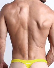 Back view of a male model wearing men’s KOKOMO YELLOW swim thong in yellow color made with Italian-made Vita By Carvico Econyl Nylon with official logo of BANG! Brand in white.