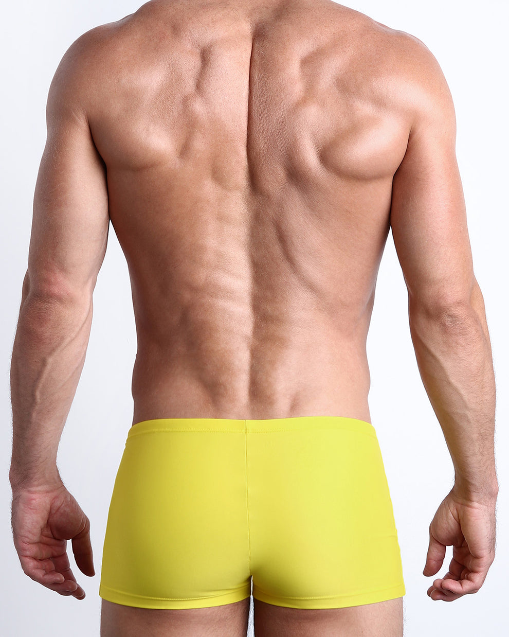 Back view of a male model wearing the KOKOMO YELLOW men’s swim trunks in a lemon yellow color made with Italian-made Vita By Carvico Econyl Nylon by the Bang! Clothes brand of men's beachwear from Miami.