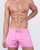 A male model wearing the LA BEACH EN ROSE - Flex Shorts by DC2 Miami. These premium shorts feature a vibrant pastel pink hue, a structured front waistband with lace-up fastening, and a sleek, modern fit.