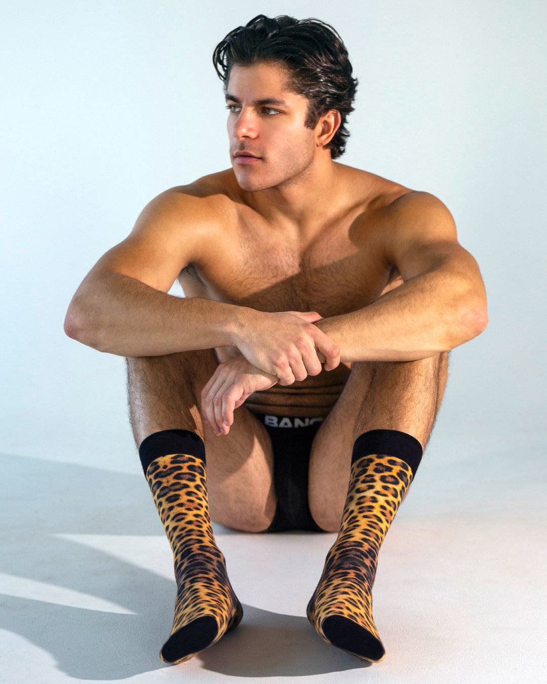 BANG! Cotton Crew Socks – Leopard + Black — model wearing soft cotton crew socks featuring bold leopard print with black cuff and toe, paired with black boxer briefs for a sleek, modern lounge look.