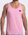 Frontal view of male model wearing the LITERALLY PINK in a solid baby pink color casual gym tank top for men by the DC2 brand of men's beachwear from Miami.