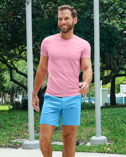 Model wearing DC2 Literally Pink Modal Cotton T-Shirt and Flamingos Do It Better Street Shorts, walking outdoors in a park setting, showcasing a bold, playful resort look.