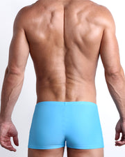 Back view of a male model wearing the MAGNET BLUE men’s swim trunks in a solid blue color made with Italian-made Vita By Carvico Econyl Nylon by the Bang! Clothes brand of men's beachwear from Miami.