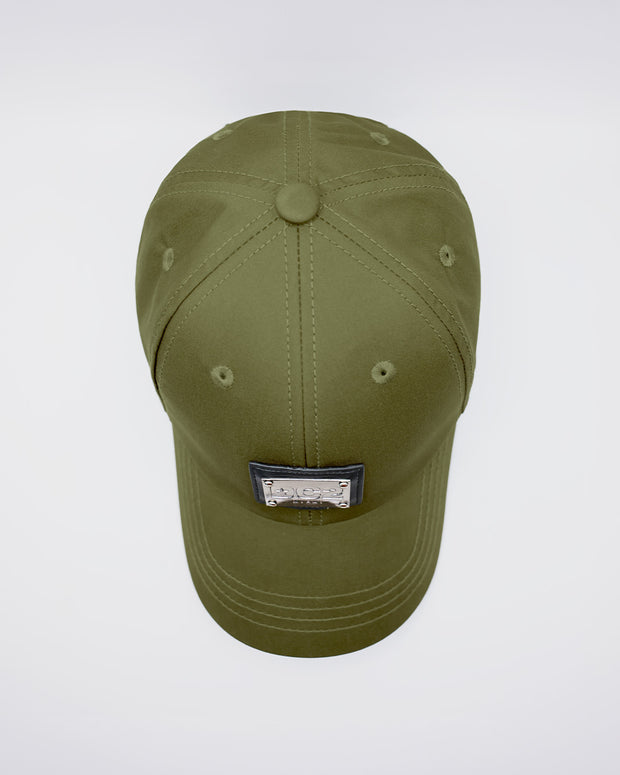 Close-up of a MAGNUM GREEN Baseball Cap with polished DC2 metallic silver plaque. Features ventilation eyelets on the cap to provide extra breathability, perfect for active wear.