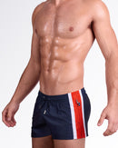 Product details graphic of Maritime Poolside Shorts — showcasing the elastic waistband, adjustable drawstring, and zippered side pocket integrated into the red stripe panel.