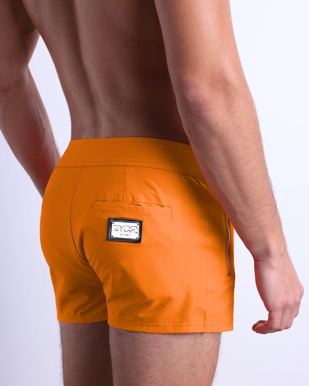 Male model wearing men’s MATCH POINT ORANGE Beach Shorts swimsuit in a orange color, complete the back zippered pocket, made by DC2 a capsule brand by BANG! Clothes in Miami.