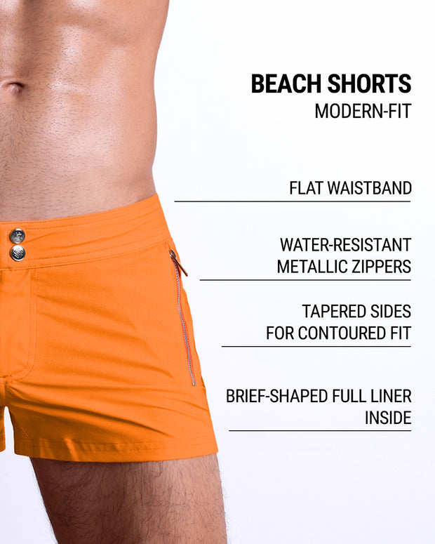 Close-up view of inseam and details of MATCH POINT ORANGE swimsuit for men, showing custom branded silver buttons.