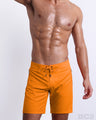 Male model wearing MATCH POINT ORANGE all-purpose Flex Boardshorts for men, premium swimwear in a solid bright orange color shorts for men. These high-quality swimwear bottoms by DC2, a men’s beachwear brand from Miami.
