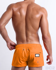 Back view of the MATCH POINT ORANGE beach Mini Shorts in a solid bright orange color, complete with a back zippered pocket, designed by DC2 a capsule brand by BANG! Clothes based in Miami.B3406