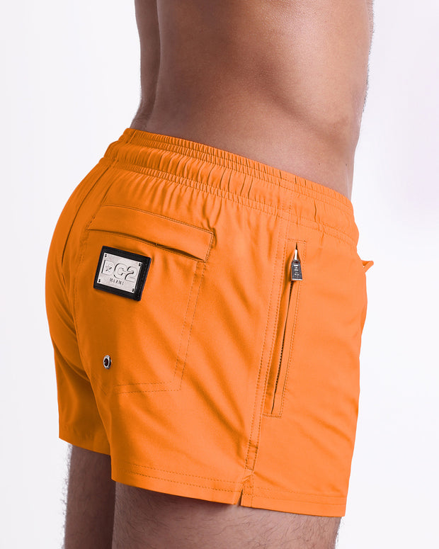 Side view of the MATCH POINT ORANGE swimsuit Poolside Shorts men’s shorter length shorts with side zipper pocket featuring a bright orange color. These high-quality swimwear bottoms by DC2, a men’s beachwear brand from Miami.