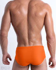 Back view of male model wearing the MATCH POINT ORANGE beach Brazilian Sunga swimwear for men by BANG! Miami in a solid bright orange color.