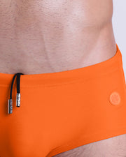 Close-up view of the MATCH POINT ORANGE men’s drawstring briefs showing black cord with custom branded metallic silver cord ends, and matching custom eyelet trims in silver.