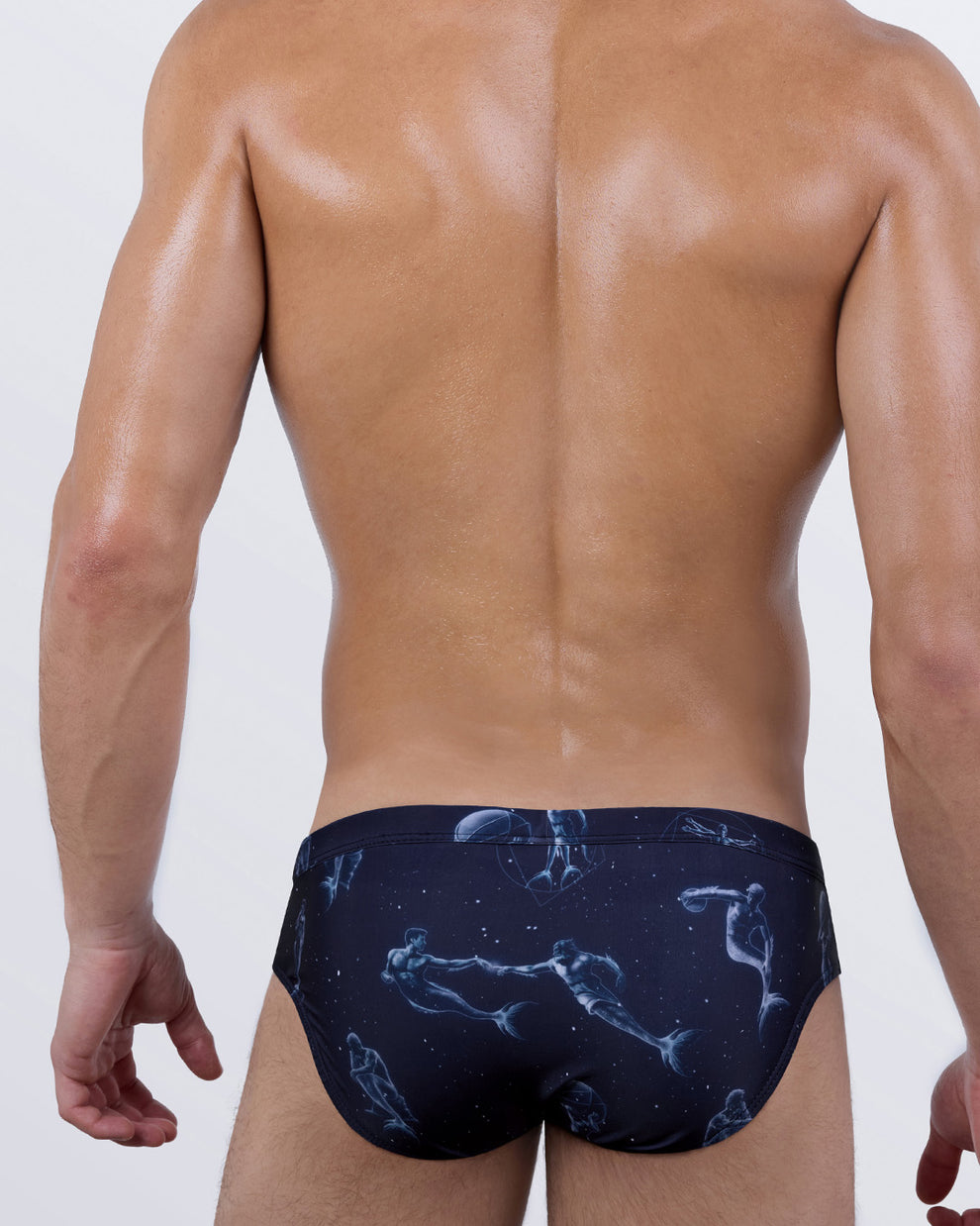 Back view of BANG! Mermen Masters Swim Brief – artistic print of muscular mermen in cosmic poses across a dark navy background, designed for sculpted comfort.