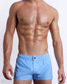 Male model wearing MONO BLUE square leg swim shorts, in a light blue color with a darker blue monogram logofor men. These high-quality swimwear bottoms by DC2, a men’s beachwear brand from Miami.