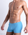 Side view of muscular male model wearing MONO BLUE Summer swimming Trunks. This swimsuit has a stylish DC2 logo motif, this swim brief were designed by DC2 in Miami.