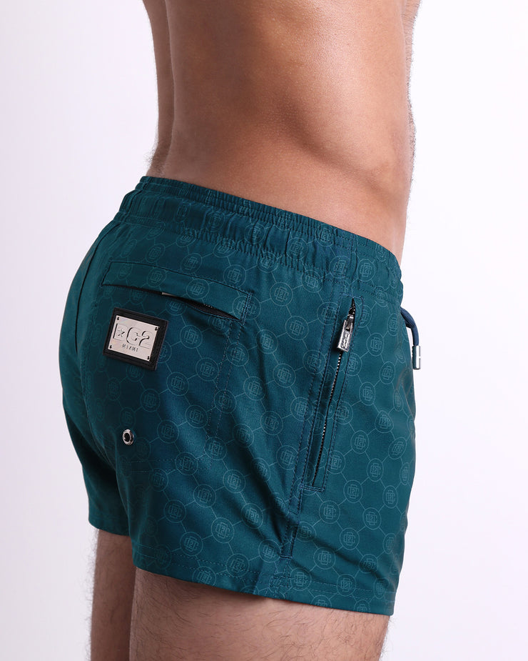 Side view of the MONO TEAL for men’s summer Poolside Shorts with dual zippered pockets. Featuring the DC2 logo motif, these shorts were designed by DC2 in Miami.