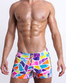 Male model wearing MOSAIC Beach Shorts, premium swimwear with a stylish multi-color mosaic shape design for men. These high-quality swimwear bottoms by BANG! Clothes, a men’s beachwear brand from Miami.