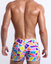 Back view of a male model wearing men’s MOSAIC Beach Shorts swimsuits a retro abstract colorful mosaic pattern, designed by BANG! Clothes in Miami.