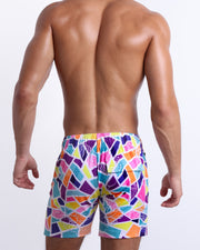 Back view of male model wearing men’s MOSAIC beach Flex Boardshorts swimming shorts. Features a crystal colorful mixed shapes design, are designed by BANG! Clothes in Miami.