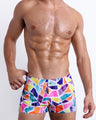 Male model wearing MOSAIC square leg swim shorts, premium swimwear with a stylish multi-color mosaic shape design for men. These high-quality swimwear bottoms by BANG! Clothes, a men’s beachwear brand from Miami.