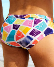  Close-up of a male model wearing MOSAIC Swim Briefs by BANG! Clothing, featuring a vibrant multicolored geometric print. These stylish men's swim briefs are designed for summer beachwear and poolside fashion.