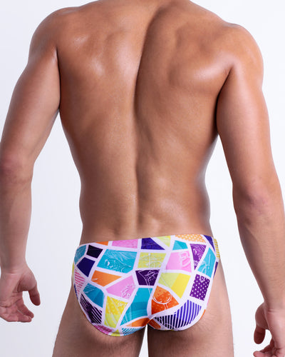 Back view of a model wearing MOSAIC men’s beach brief features a crystal colorful mixed shapes design, is designed by BANG! Clothes in Miami.