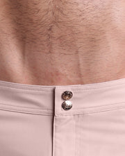Close-up view of inseam and details of NAKED PINK swimsuit for men, showing custom branded golden buttons.