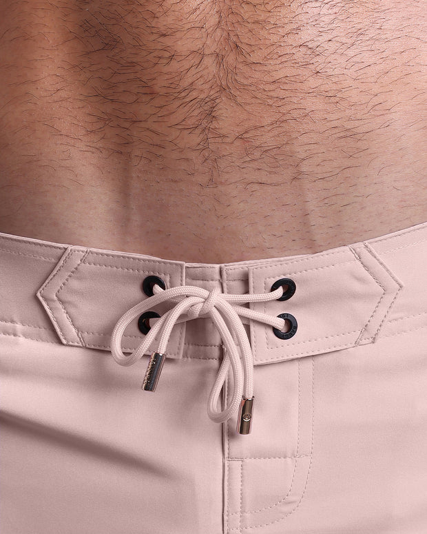 Close-up view of men’s summer Flex shorts by BANG! clothing brand, showing light pink color cord with custom-branded golden cord ends, and matching custom eyelet trims in gold.