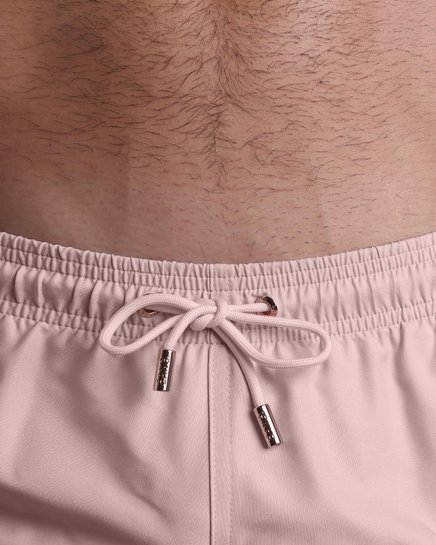 Close-up view of the NAKED PINK men’s summer shorts, showing pink cord with custom branded golden cord ends, and matching custom eyelet trims in gold.