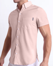 Side view of a masculine model wearing the men’s NAKED PINK Summer button-down shirt in a light pink color with the official logo of BANG! Brand.