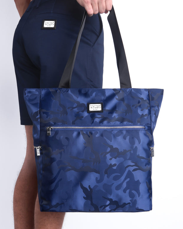 The NAVY BLUE CAMO Poolside Tote Bag in a navy blue camouflage print. This perfect day tripper bag protect your belongings from spills and splashes designed by DC2 in Miami.