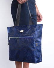 Side view of the NAVY BLUE CAMO Poolside Tote Bag Foldable/Portable by DC2 brand. Features smooth zipper in the front and the side, water resistant fabric, and the DC2 logo in a metallic silver plaque.