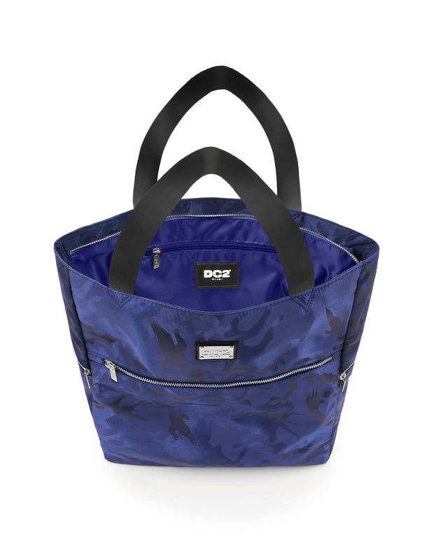 Top view of the NAVY BLUE CAMO Poolside Tote Bag by DC2 Miami, showcasing the spacious interior with a visible DC2 Miami logo label. The bag features a blue camouflage pattern with sturdy black handles and multiple zippered compartments for secure storage.