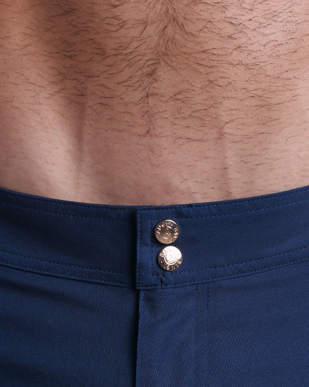 Close-up view of inseam and details of NAVY BOOMER swimsuit for men, showing custom branded golden buttons.